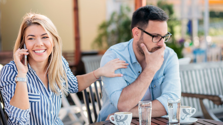 woman talking on phone in front of man