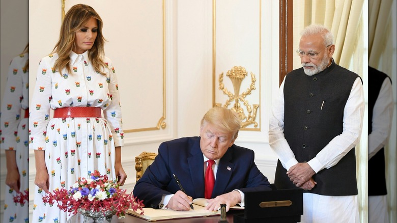 Melania watching Donald signing document