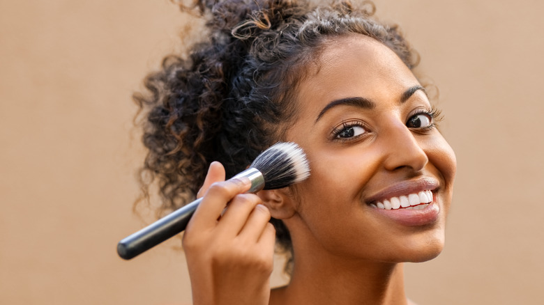 Woman dusting on makeup with a brush