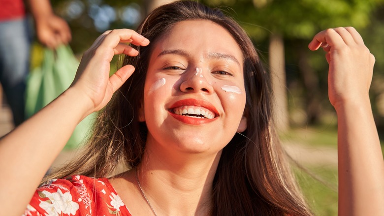 Woman smiling sunscreen on face