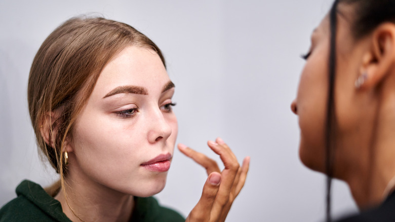 A makeup artist applying primer to a woman