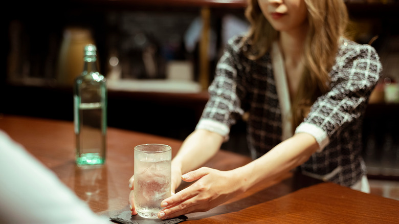 woman taking water from bar