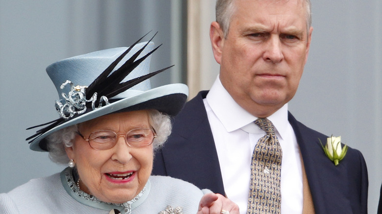 Prince Andrew looks grumpy behind the queen pointing