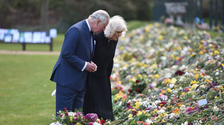 Charles and Camilla looking at Prince Philip's remembrance flowers