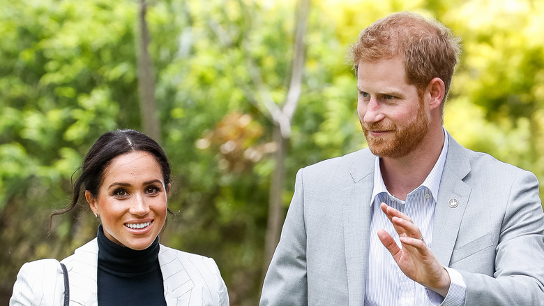 Prince Harry and Meghan Markle waving and walking