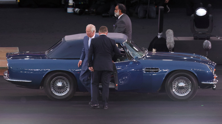 Prince Chalres alighting from his blue Aston Martin DB6