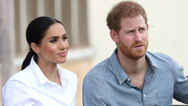 Meghan Markle and Prince Harry listening to speaker