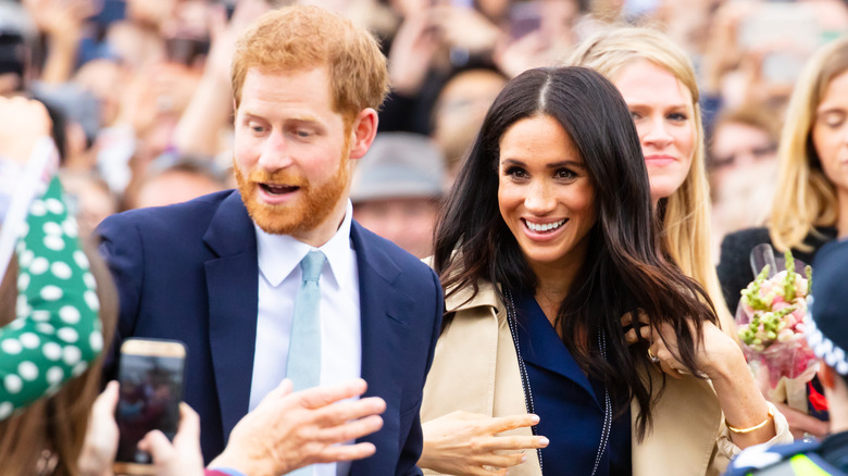 Prince Harry and Meghan Markle greeting a crowd of fans