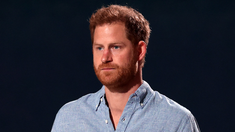 Prince Harry posing in front of blue backdrop