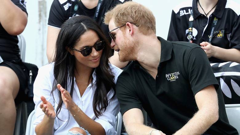 Prince Harry leaning in and whispering to Meghan Markle