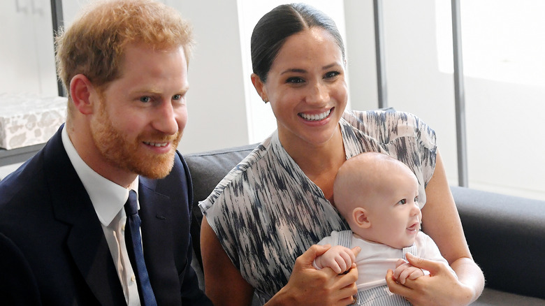 Prince Harry and Meghan Markle smiling with Archie