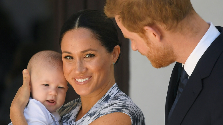 Prince Harry looking at Meghan Markle holding Archie