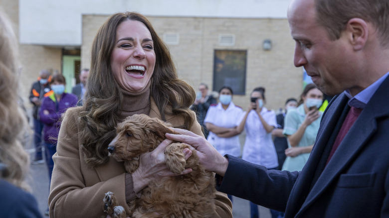 Kate Middleton holding a service puppy with Prince William