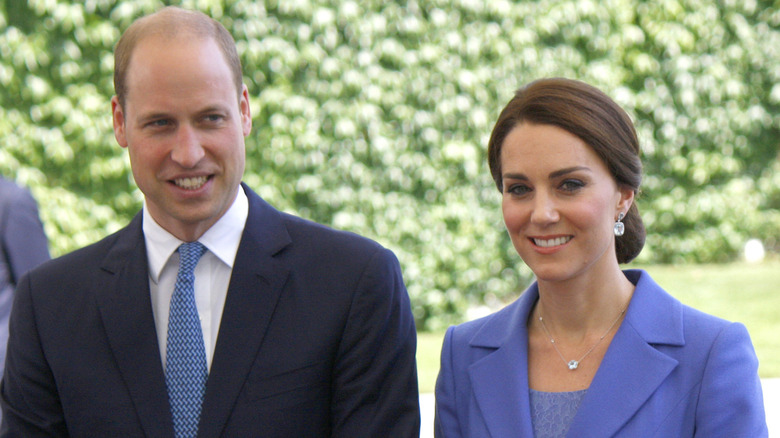 Prince William and Kate Middleton outside, smiling at other people.