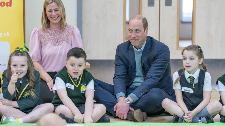 Prince William makes a funny face next to some children