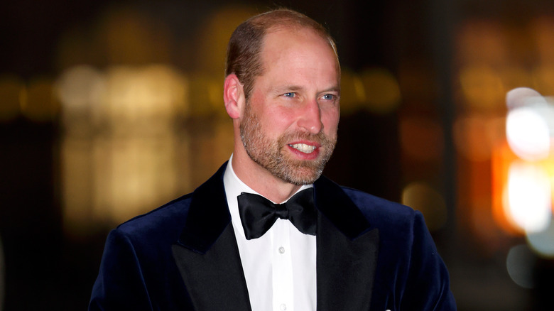 Prince William smiles while wearing a navy blue suit