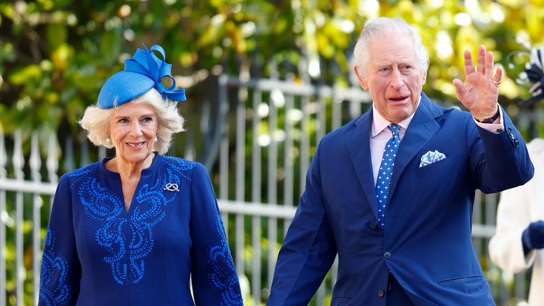 King Charles III and Camilla Parker Bowles wearing blue outfits and greeting the public