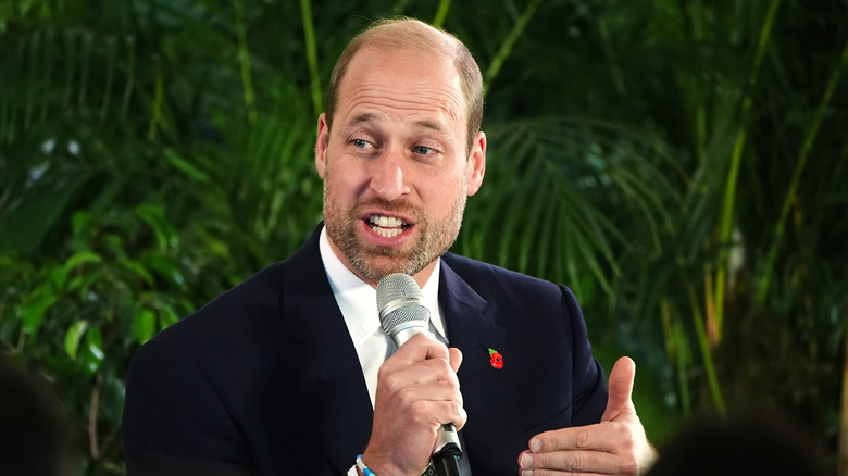 Prince William with a beard speaking into a microphone