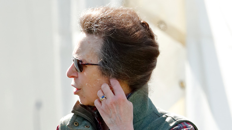 Princess Anne wearing sunglasses, turning head