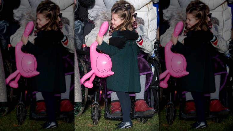 Princess Catherine hugging woman & holding pink inflatable flamingo