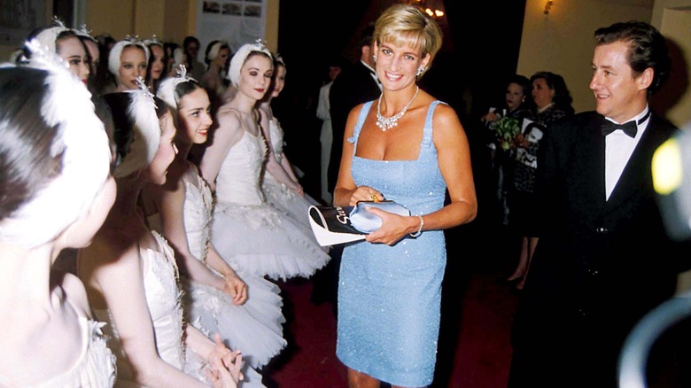 Princess Diana smiling in a blue dress at the ballet