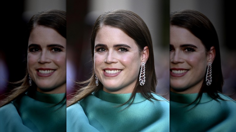 Closeup of Princess Eugenie smiling in green and wearing long, dropdown diamond earrings