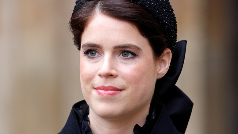 Princess Eugenie smiling and wearing dark blue beaded hat