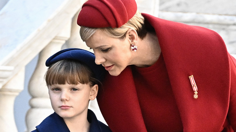 Princess Charlene whispers into Princess Gabriella's ear