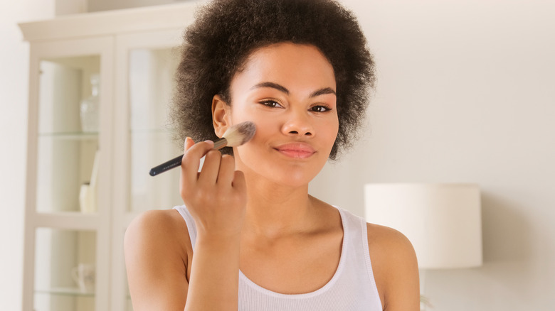 Woman applying makeup powder