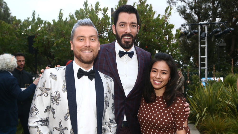 Drew Scott and his wife, Linda Phan, pose for a picture with Lance Bass on the red carpet. 