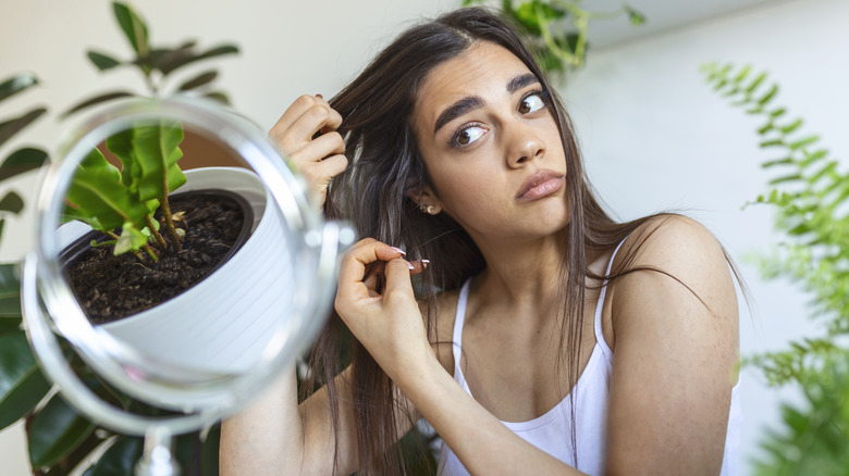 Woman looking at hair in mirror