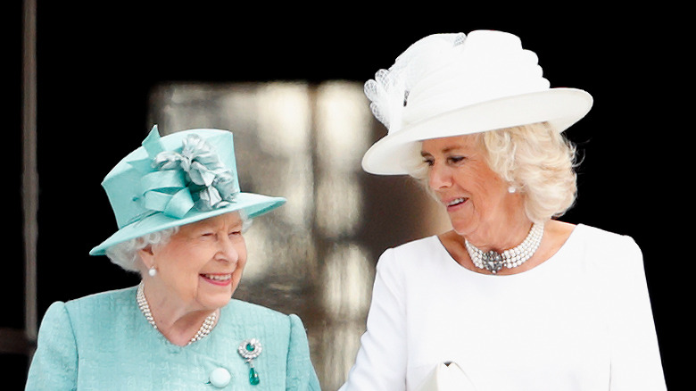 Queen Elizabeth and Camilla Parker Bowles in hats talking