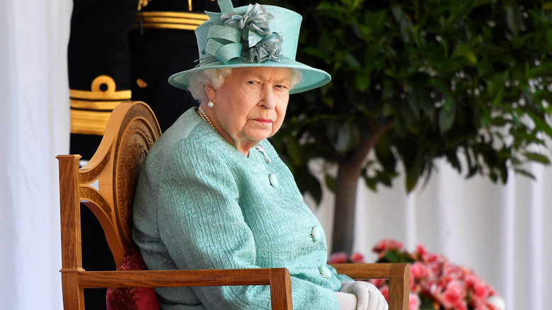 The queen looks grumpy while sitting in a chair