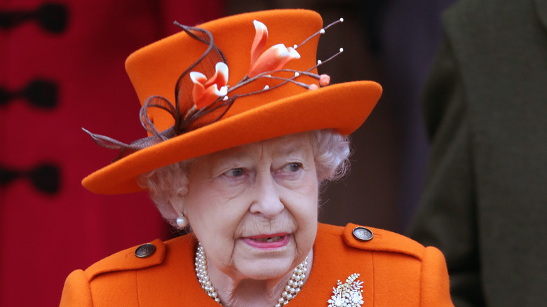 The queen grimaces in an orange outfit