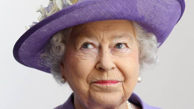 Queen Elizabeth II with mischievous look wearing purple hat