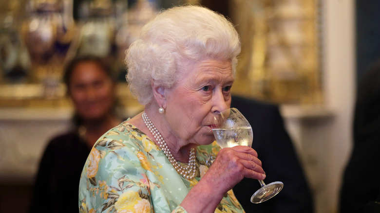 Queen Elizabeth drinking at an event