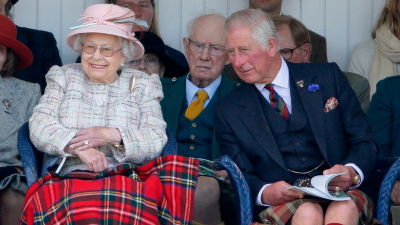 Queen Elizabeth smiling and Prince Charles watching the Braemar Games 