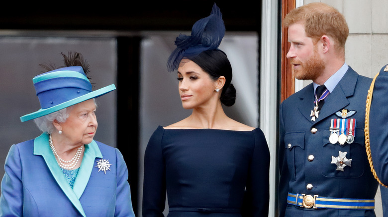 Queen Elizabeth standing next to Meghan Markle and Prince Harry