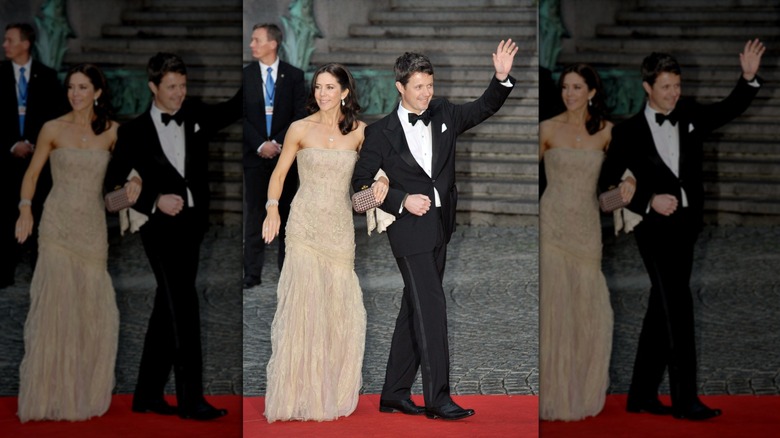 Princess Mary and Prince Frederik of Denmark waving and walking on red carpet in formal attire