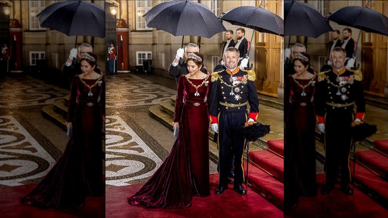 Princess Mary and Prince Frederik of Denmark smiling in formal wear under umbrellas