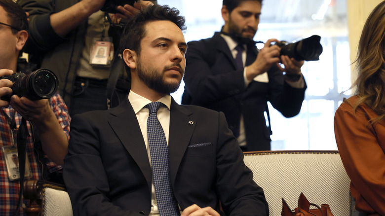 Crown Prince Hussein sitting , looking away