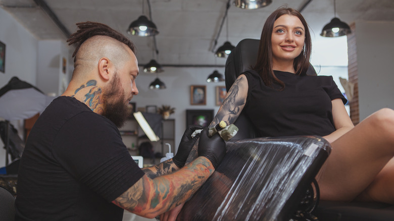 A tattoo artist tattooing a woman's arm