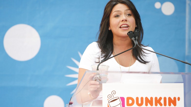 Rachael Ray talking into a microphone at a Dunkin' Donuts podium