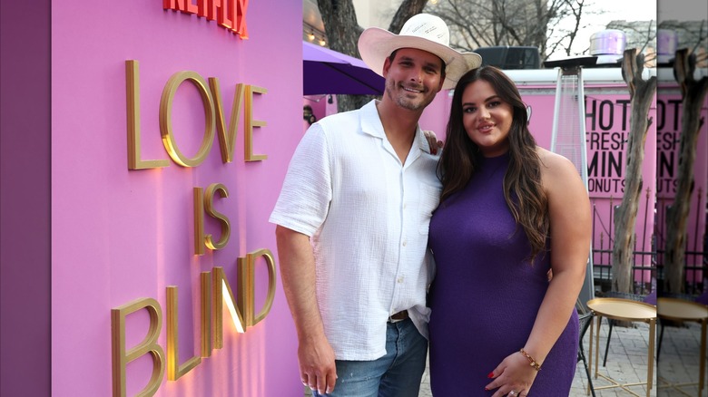 Alexa and Brennon pose in front of a "Love Is Blind" sign