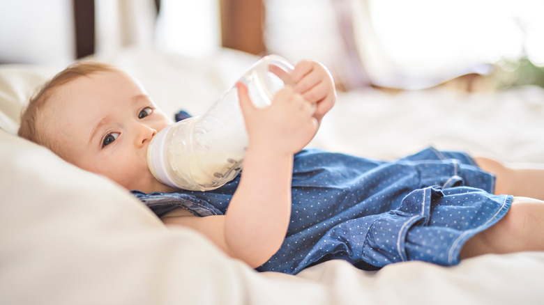 baby in blue dress drinking bottle