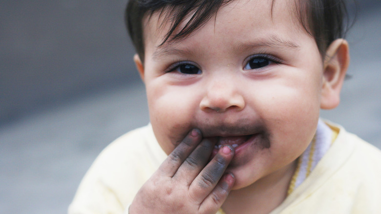 little boy with dirt on his fingers and mouth