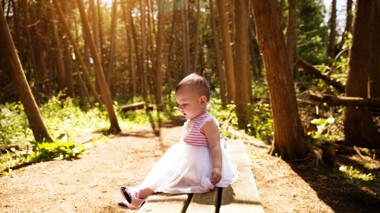 toddler in tutu sitting in the forest