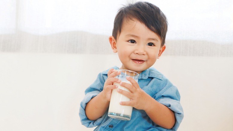 Baby holding glass of milk