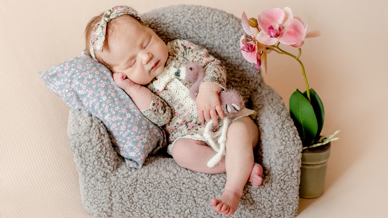 Baby girl sleeping next to orchid