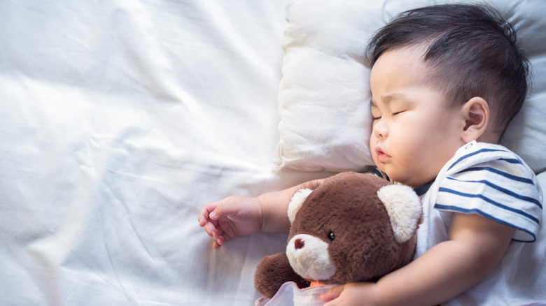 Baby boy sleeping with teddy bear